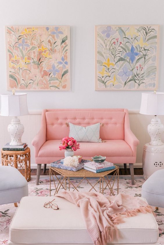 a feminine living room with a pink loveseat and grey chairs, a neutral ottoman, a floral rug and pastel watercolors is amazing