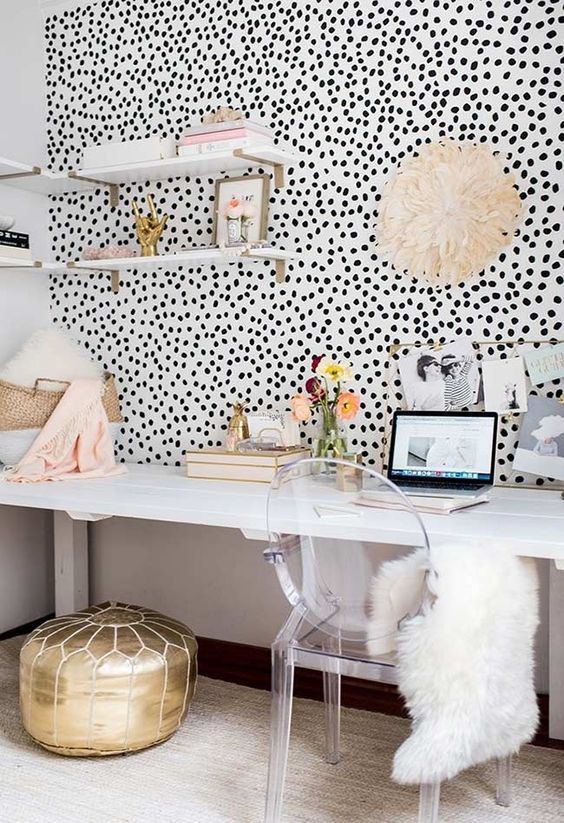 a feminine workspace with a Dolmatin print wall, a large white desk and a clear chair, open shelves and a shiny gold pouf is wow