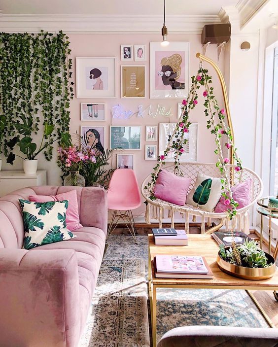 a gorgeous girlish space with pink walls, a mauve sofa and a hot pink chair, a pendant floral chair with pink pillows, potted greenery and a gallery wall