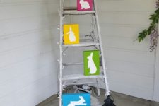 a ladder with colorful bunnies, a lantern with candles and colorful potted tulips in a wooden planter