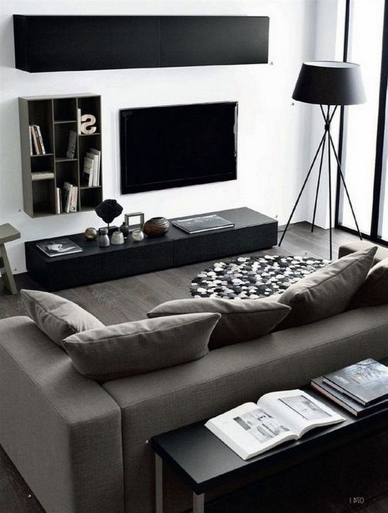 a minimalist masculine space with black and graphite grey furniture, wall-mounted storage units and a floor lamp