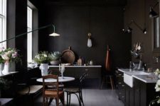 a moody vintage kitchen with white countertops, wall lamps and floral arrangements