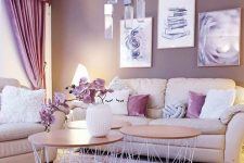 a pretty and chic girlish space with neutral seating furniture, mauve walls, purple curtains and pillows, a cluster of pendant lamps and round coffee tables