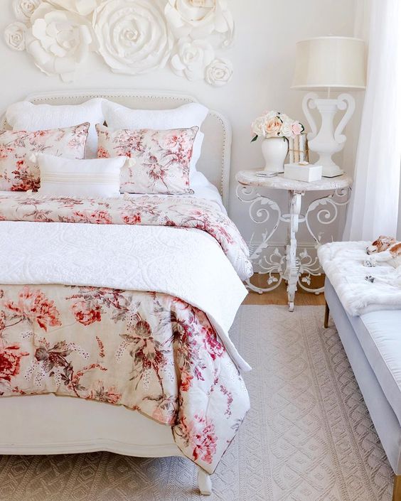 a refined Parisian style bedroom with chic furniture, floral bedding and a floral applique on the wall plus some blooms