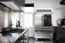 a sleek black kitchen with metal countertops, a large metal hearth and a sleek metal backsplash