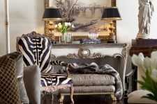 a sophisticated living room in neutrals, with a zebra print rug, vintage carved furniture pieces, black table lamps and cool art