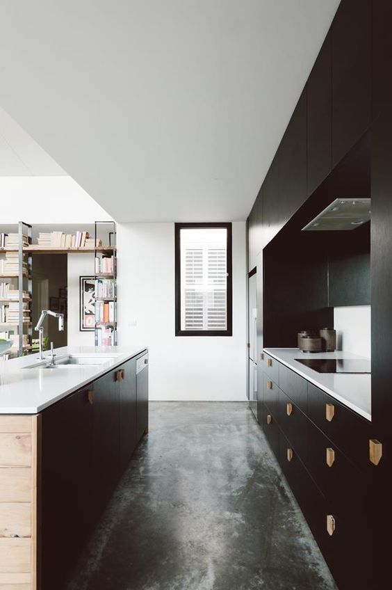 a stylish black kitchen with wooden handles, white countertops and a window to fill the space with light
