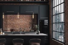 a stylish moody kitchen with black cabinets, gold touches, a large kitchen island and red brick walls