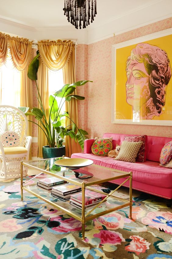 a super bright feminine living room with a bol floral print rug, a hot pink sofa, a statement artwork, yellow curtains and colorful pillows