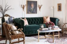 a vintage-inspired living room with a dark green sofa, leopard print chairs, a coffee table and layered rugs plus cool and chic art