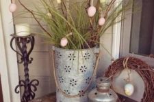 a wreath with a hanging egg and a laser cut bucket with branches, grass and colorful eggs