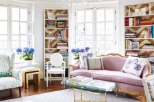 an elegant and refined feminine living room with a chic lilac sofa, bookcases, a printed rug and chairs, a glass coffee table and a crystal chandelier