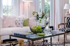 an elegant living room with a creamy sofa and pastel pillows, a black coffee table, zebra print chairs and a rug and some greenery to refresh the space