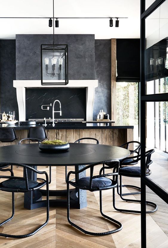 an elegant moody kitchen with a wooden kitchen island with a black countertop and a chalkboard plus pendant lamps