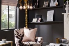 an urban glam living room with matte black walls, an animal print chair, gold frame coffee tables, a gold tree-like floor lamp