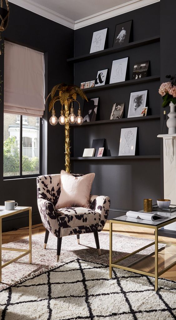 an urban glam living room with matte black walls, an animal print chair, gold frame coffee tables, a gold tree-like floor lamp