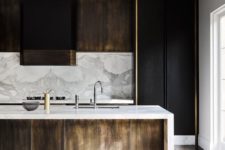 black and light-colored wooden cabinets, a marble backsplash and countertops for a chic touch