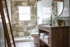 a barn bathroom with a stone wall, wooden beams, a wooden vanity, mirrors and white tiles on the wall
