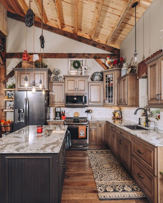 a barn kitchen with a wooden ceiling and wooden beams, stained shaker style cabinets, a dark stained kitchen island and stone countertops