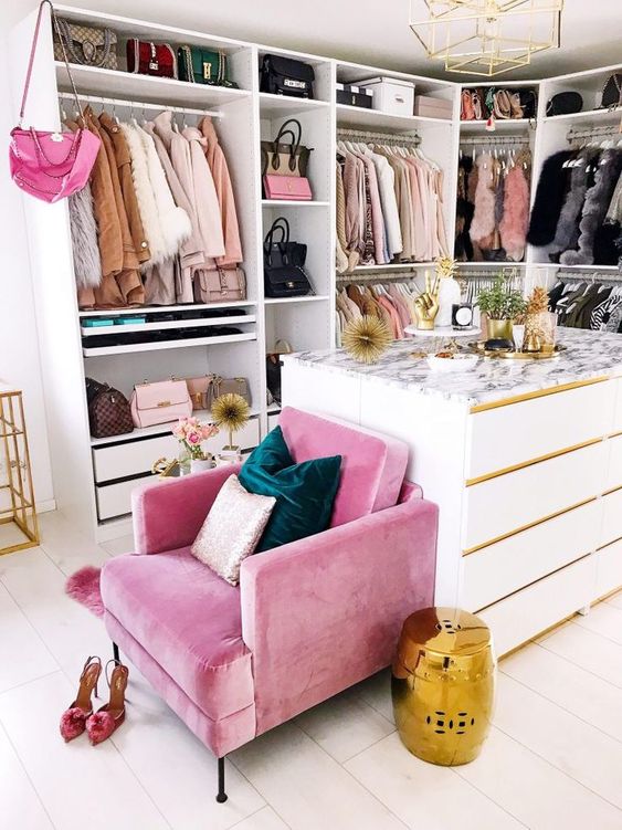 a bright and glam closet with an open storage unit and drawers, a white cabinet for storage, a hot pink chair and other hot pink touches