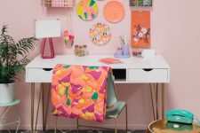 a bright feminine home office with a blush wall, a bright gallery wall, a colorful chair and gold touches