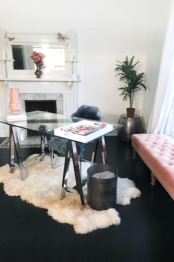 a catchy feminine home office with a glass trestle desk, a white fur rug, a tile clad fireplace and a blush daybed