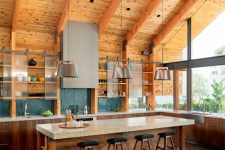 a contemporary barn kitchen with skylights, wooden beams, stained cabinets and a kitchen island, cabinets with sliding doors and metal lamps