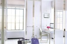 a glam and chic closet with wardrobes with sleek doors to keep it uncluttered, a bold chandelier and shiny stools