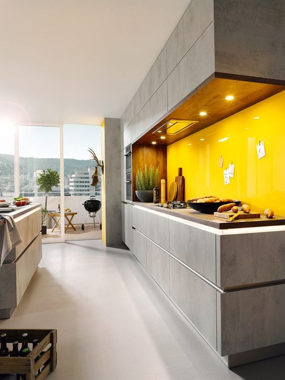 a grey concrete-looking kitchen with dark staiend butcherblock countertops and a bold glossy yellow glass backsplash