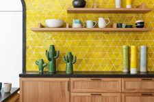 a light-stained kitchen with black countertops, open shelves and a super bold yellow triangle backsplash and bold accessories
