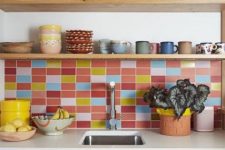 a light-stained modern kitchen with white stone countertops and a colorful tile backsplash in pink, red, blue and yellow that creates a mood in the space