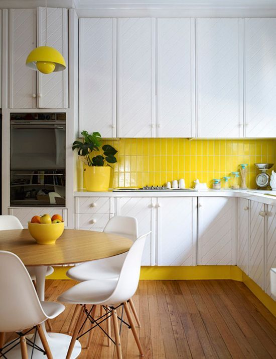 a modern white kitchen with a bold yellow skinny tile backsplash, lamp and other accents that echo with the backsplash