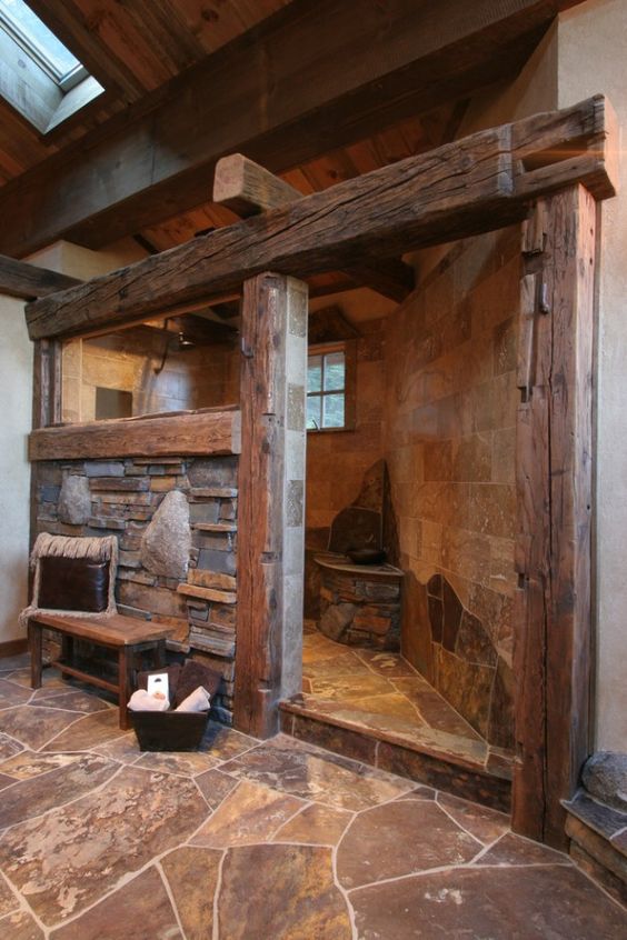 a stone barn bathroom with wide wooden beams, wooden furniture and a skylight to fill the space with light