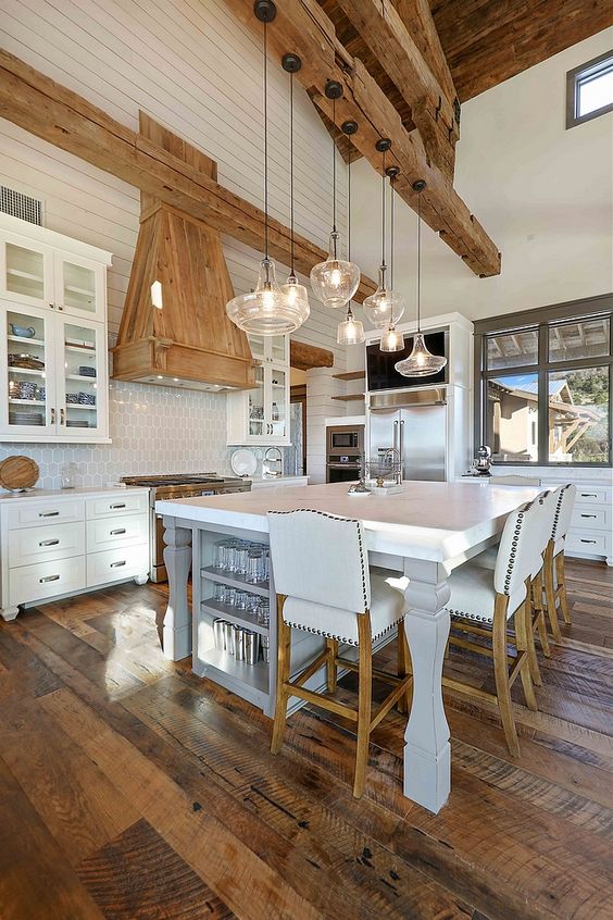 a white barn kitchen with a planked ceiling, wooden beams, white cabinetry, a large kitchen island that doubles as a table