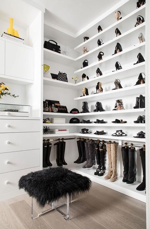 an elegant neutral closet with open shoe and bag shelves, with closed storage, a black faux fur stool and more black touches