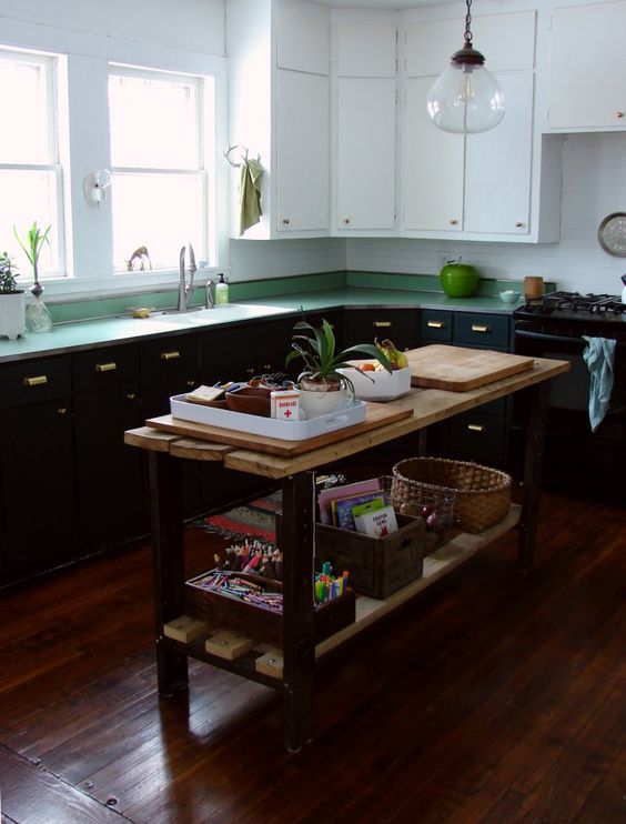 a black and white kitchen with green countertops, white tiles, a vintage wooden kitchen island with a planked countertop