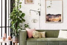 a boho chic living room with white brick walls, potted greenery, a green sofa and pink touches