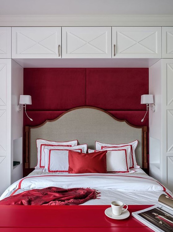 a bold red and white bedroom with a storage unit in white, a bed integrated into a niche, a red bench and red bedding