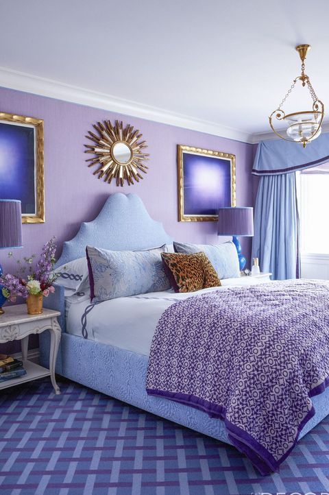 a bright purple bedroom with gold details, a pretty pendant lamp, some refined nightstands and a sunburst mirror