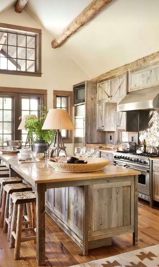 a chalet kitchen with reclaimed aged wood cabinets, a tile backsplash and stainless steel applainces and a large reclaimed wood kitchen island