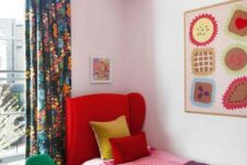 a colorful guest bedroom with a red upholstered bed, colorful bedding, a bright artwork, a white and red pendant lamp and a green chair