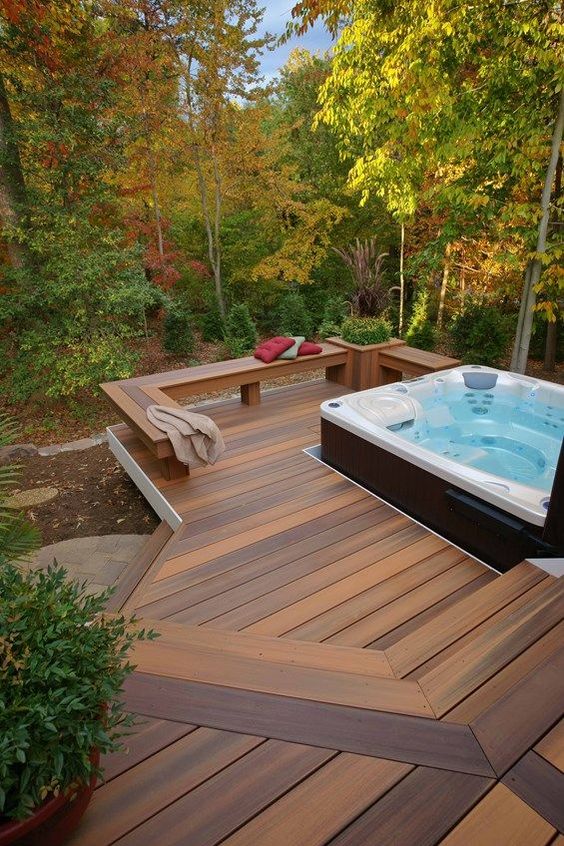 a contemporary deck with a built-in bench with a planter and a large jacuzzi plus a view to the forest