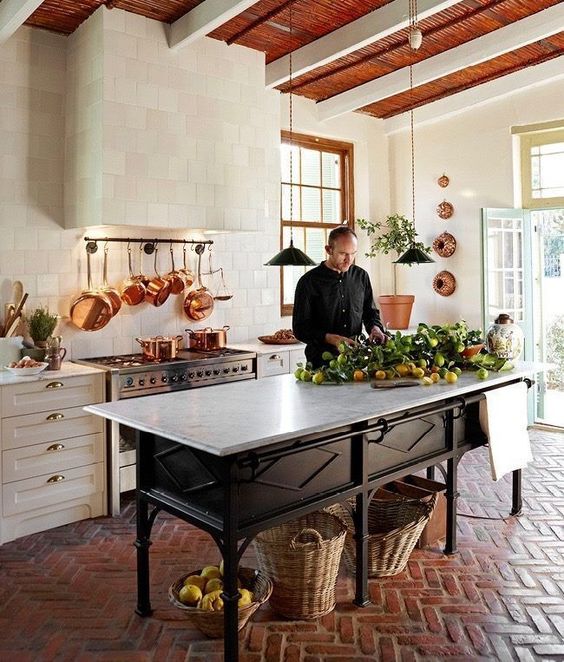 a fab neutral kitchen with shaker style cabinets, a white tile backsplash and a hood clad with them, a vintage wooden table as a kitchen island, with a stone countertop