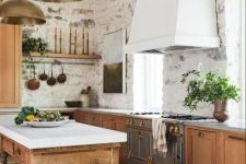 a gorgeous farmhouse kitchen with stained cabinets, stainless steel appliances, a white hood, a vintage kitchen island of wood