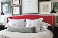 a grey bedroom spruced up with lots of artworks and a red upholstered bed