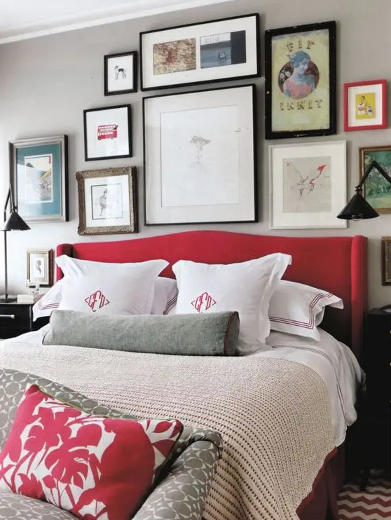 a grey bedroom spruced up with lots of artworks and a red upholstered bed