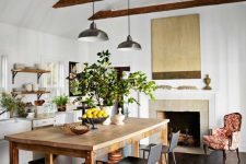 a lovely white farmhouse kitchen with open shelves, a fireplace, a large wooden table that doubles as a kitchen island and black stools