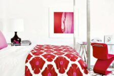 a luxurious white bedroom with a hot red chair, artwork and a floral bedspread