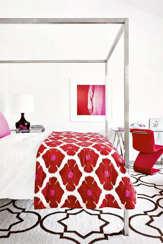 a luxurious white bedroom with a hot red chair, artwork and a floral bedspread