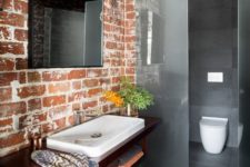 a minimalist bathroom done in greys with a brick wall that adds character and interest to the space